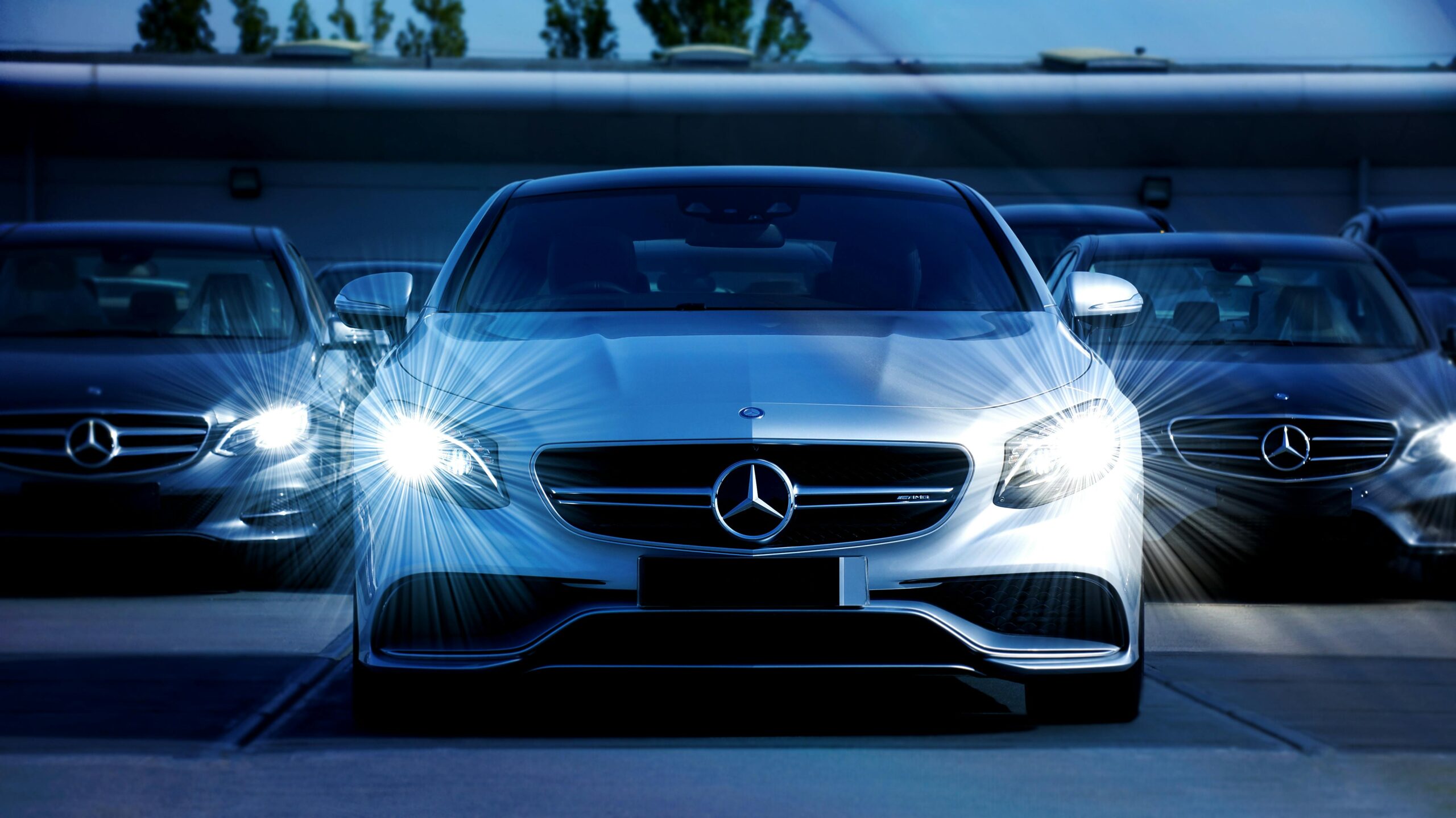 Front view of a lineup of Mercedes-Benz cars with bright headlights, showcasing luxury and elegance in car in hire kochi