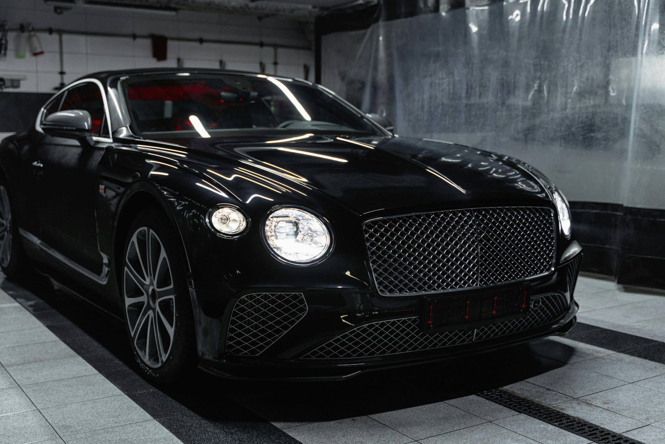 Sleek black luxury car in a modern indoor car wash setting, showcasing elegance and sophistication in car in hire kochi